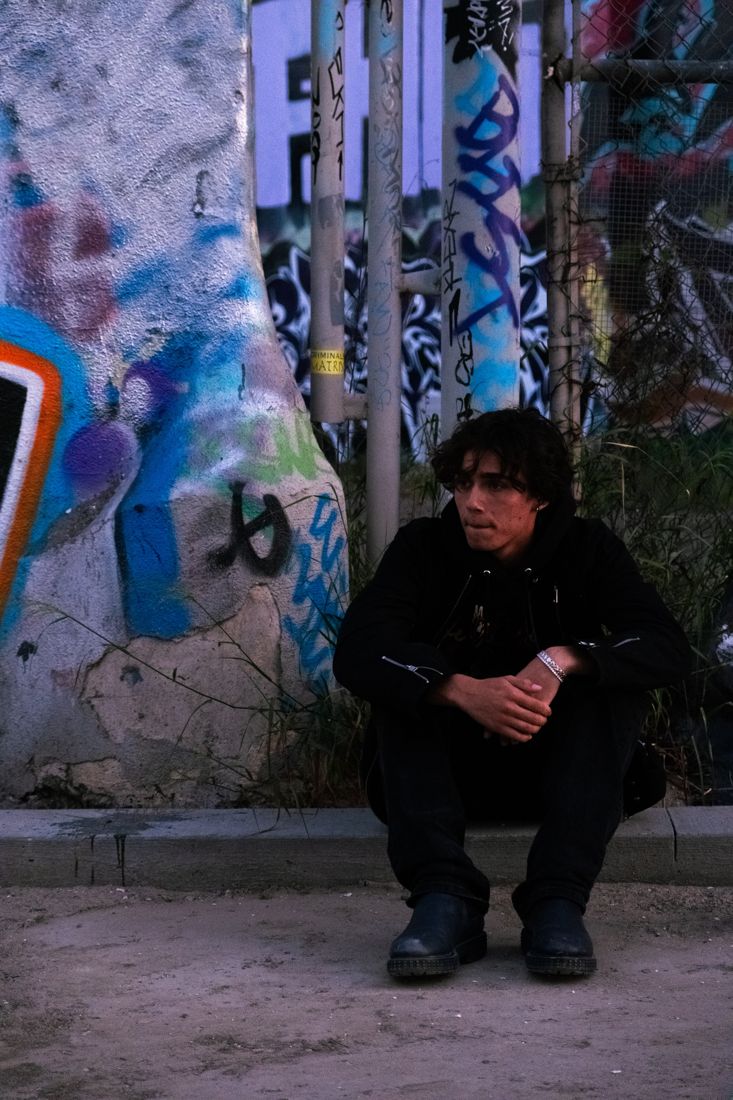 BR!X crouching by a graffiti wall in Los Angeles